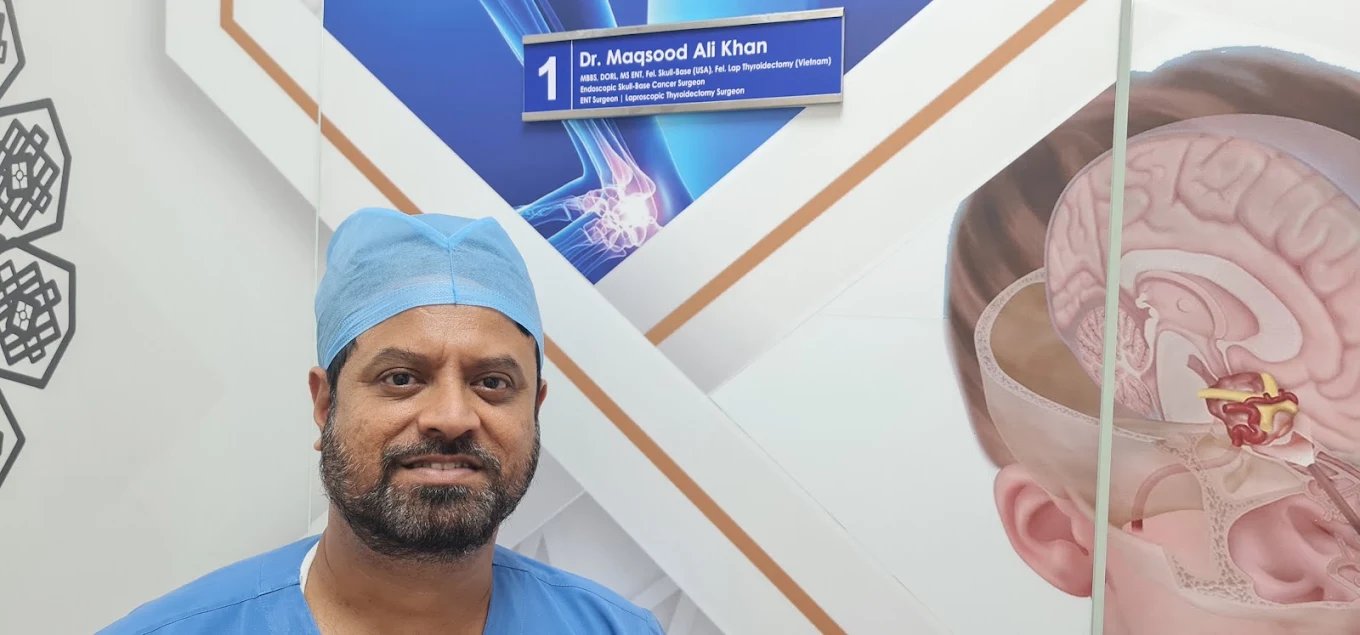 Dr. Maqsood Ali Khan beside his name board at the clinic